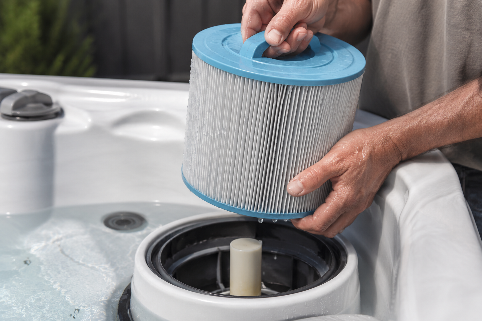 Person replacing a filter in a hot tub with a close-up of the filter and hands.